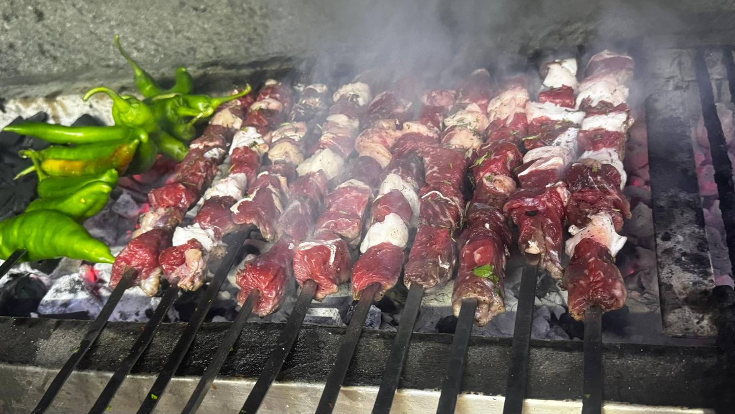 Mangalda közlenen kuşbaşı kebap şişleri ve yeşil biberler